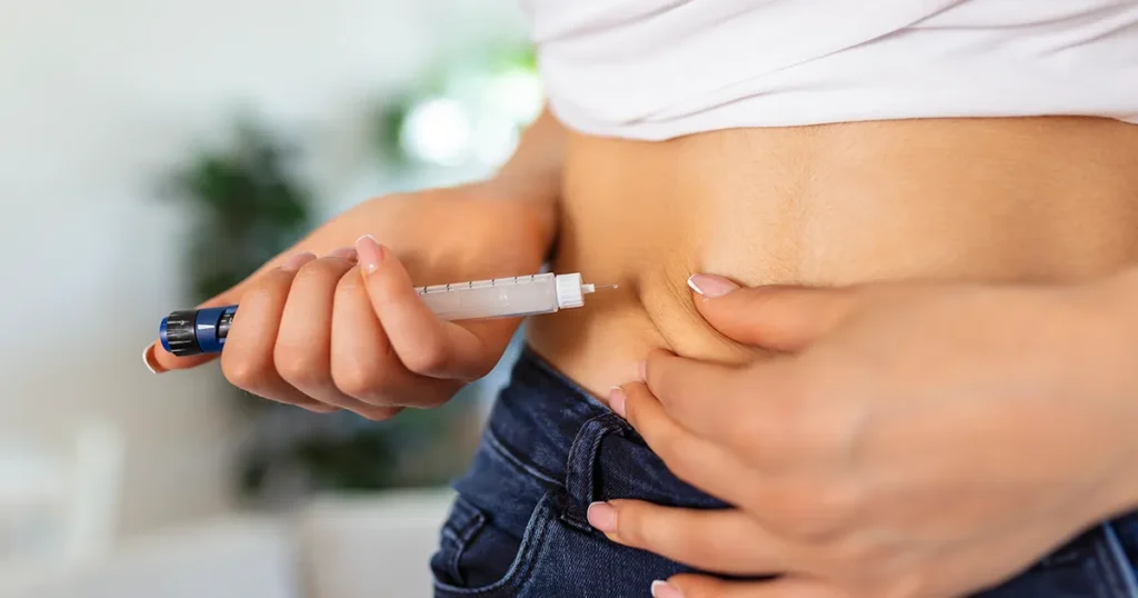 Woman using GLP-1 injection pen in abdomen for weight loss, demonstrating self-administration of GLP-1 medications