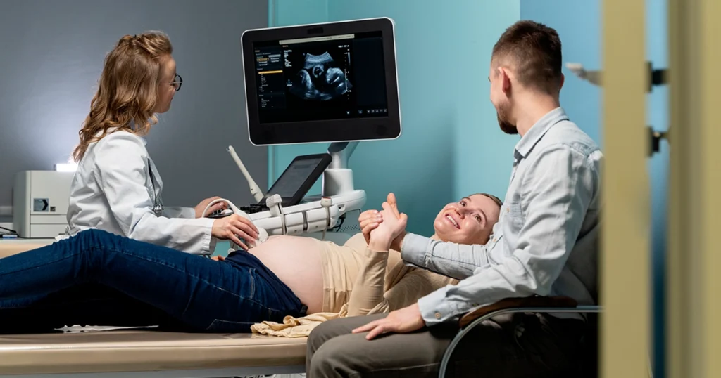 Pregnant woman having an ultrasound scan during a prenatal checkup with her partner beside her