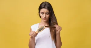 Woman looking at hair loss in brush — hormonal hair loss in women