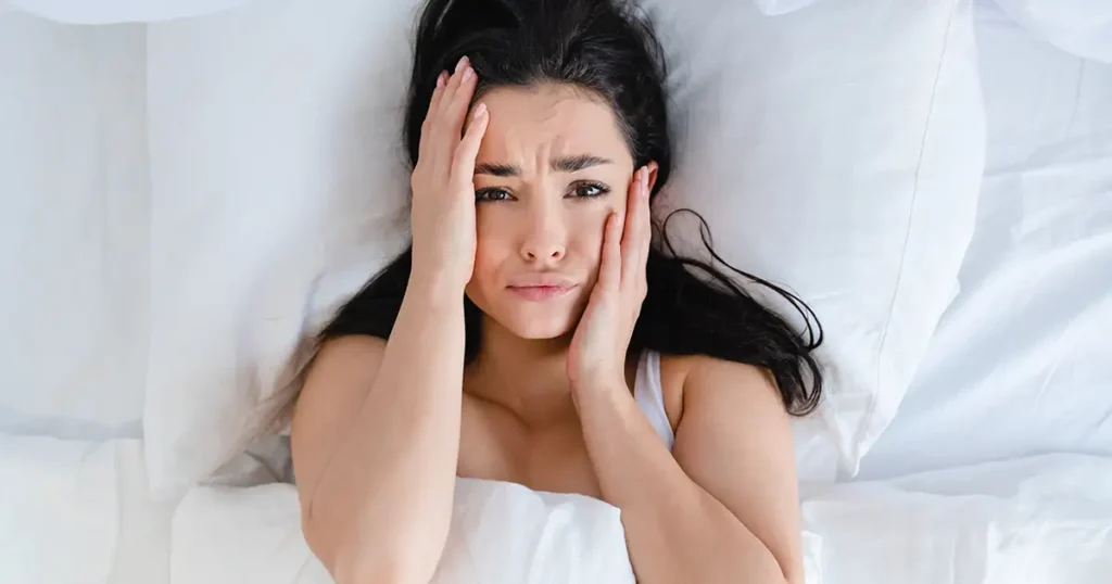 Woman lying awake in bed at 3 AM struggling with hormone insomnia and disrupted sleep