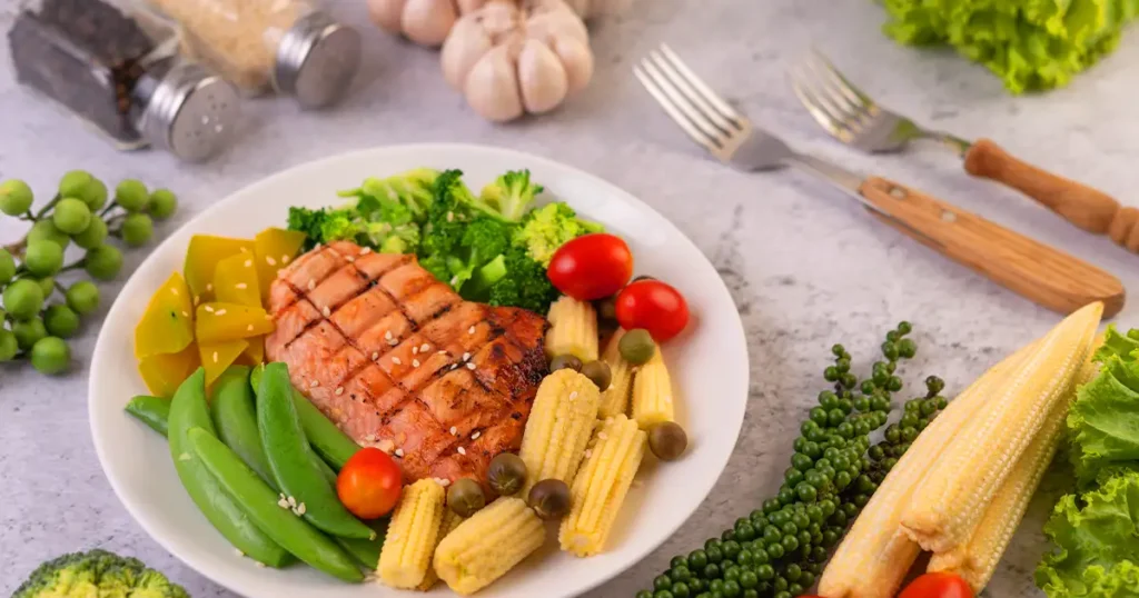 PCOS-friendly meal with grilled salmon, broccoli, snap peas, and colorful vegetables for hormone balance