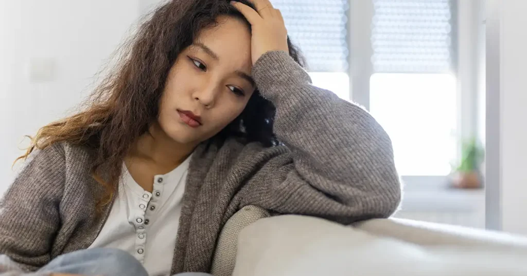 Tired woman on couch experiencing perimenopause symptoms including fatigue and mood changes